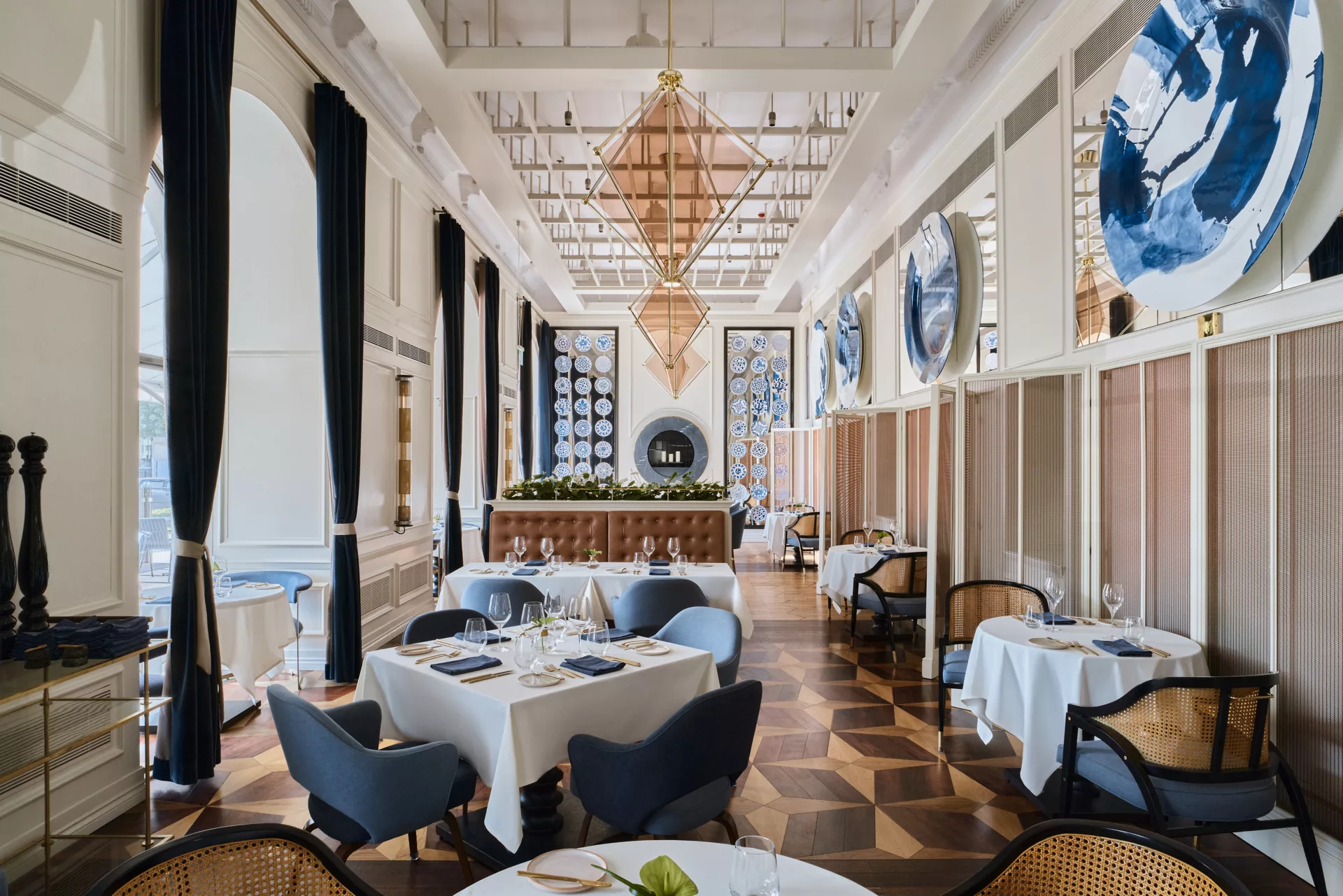 A pyramid stack of empty crystal champagne coupe glasses on a glass table with a dark background and soft lighting.