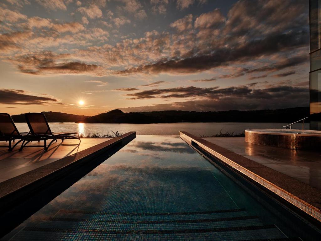 A pyramid stack of empty crystal champagne coupe glasses on a glass table with a dark background and soft lighting.