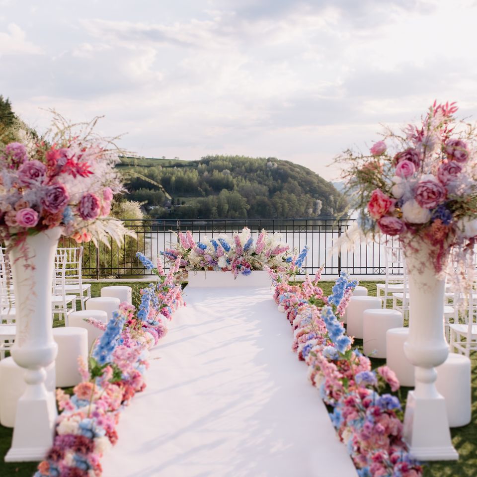 A pyramid stack of empty crystal champagne coupe glasses on a glass table with a dark background and soft lighting.