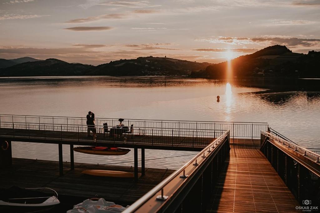 A pyramid stack of empty crystal champagne coupe glasses on a glass table with a dark background and soft lighting.