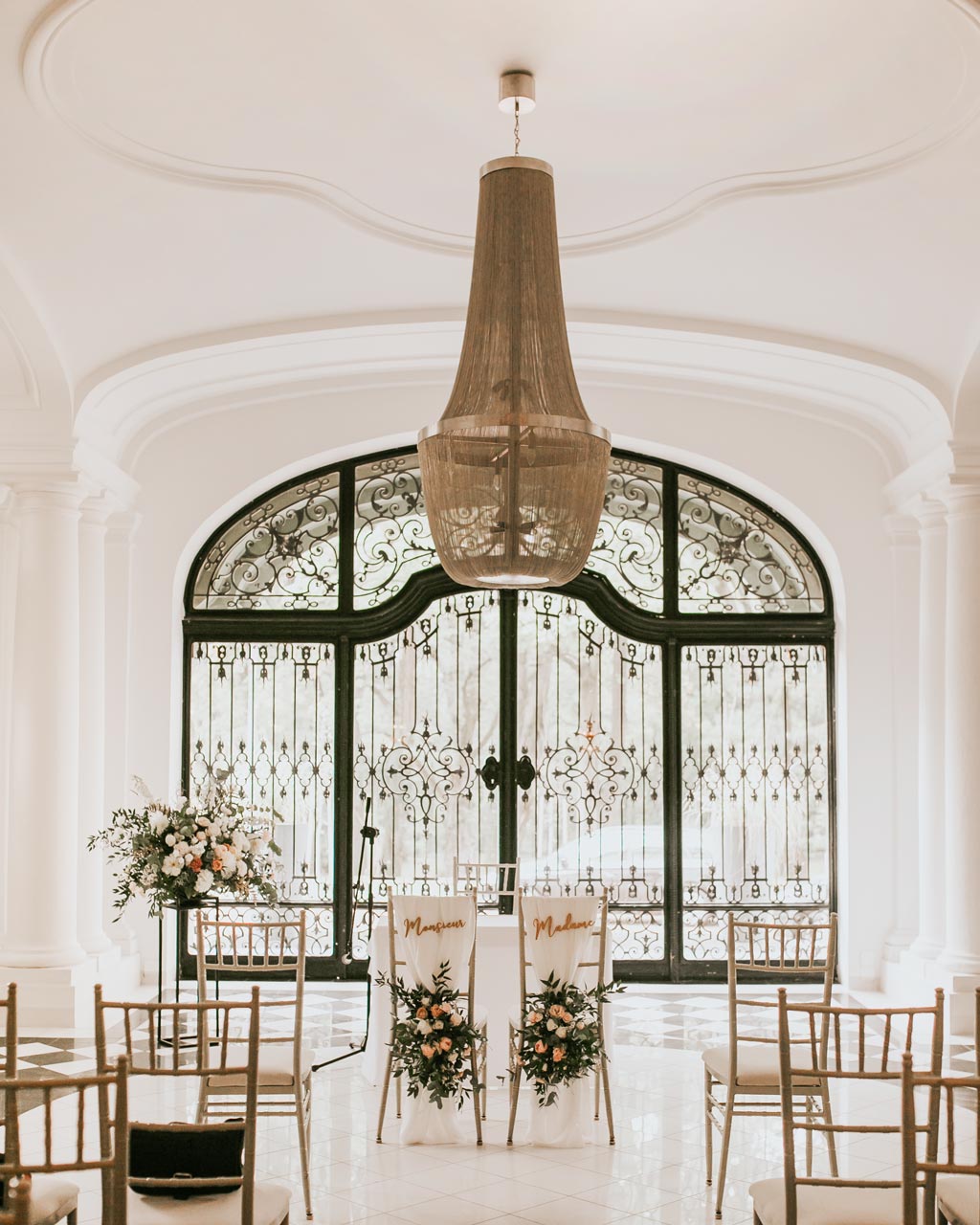 A pyramid stack of empty crystal champagne coupe glasses on a glass table with a dark background and soft lighting.