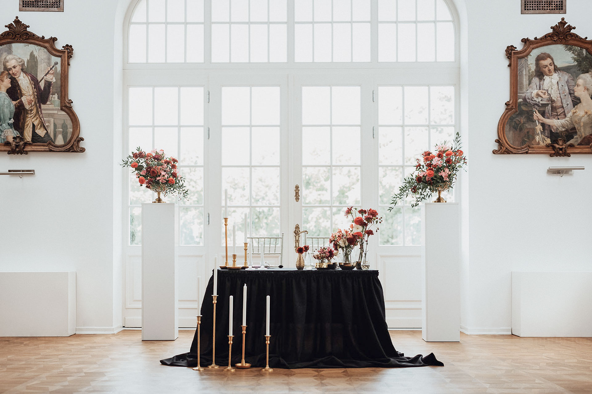 A pyramid stack of empty crystal champagne coupe glasses on a glass table with a dark background and soft lighting.