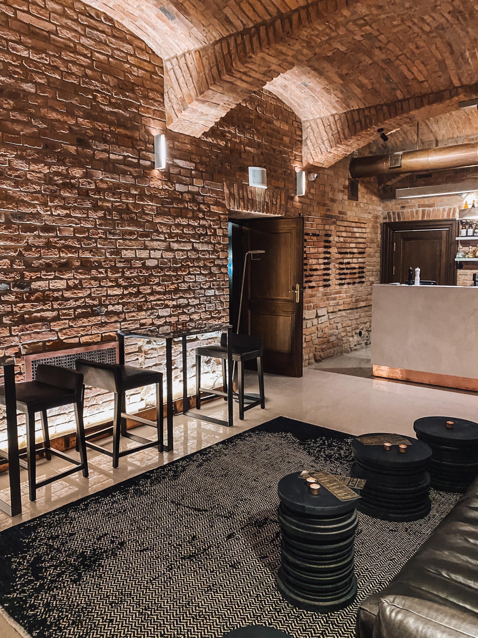 A pyramid stack of empty crystal champagne coupe glasses on a glass table with a dark background and soft lighting.