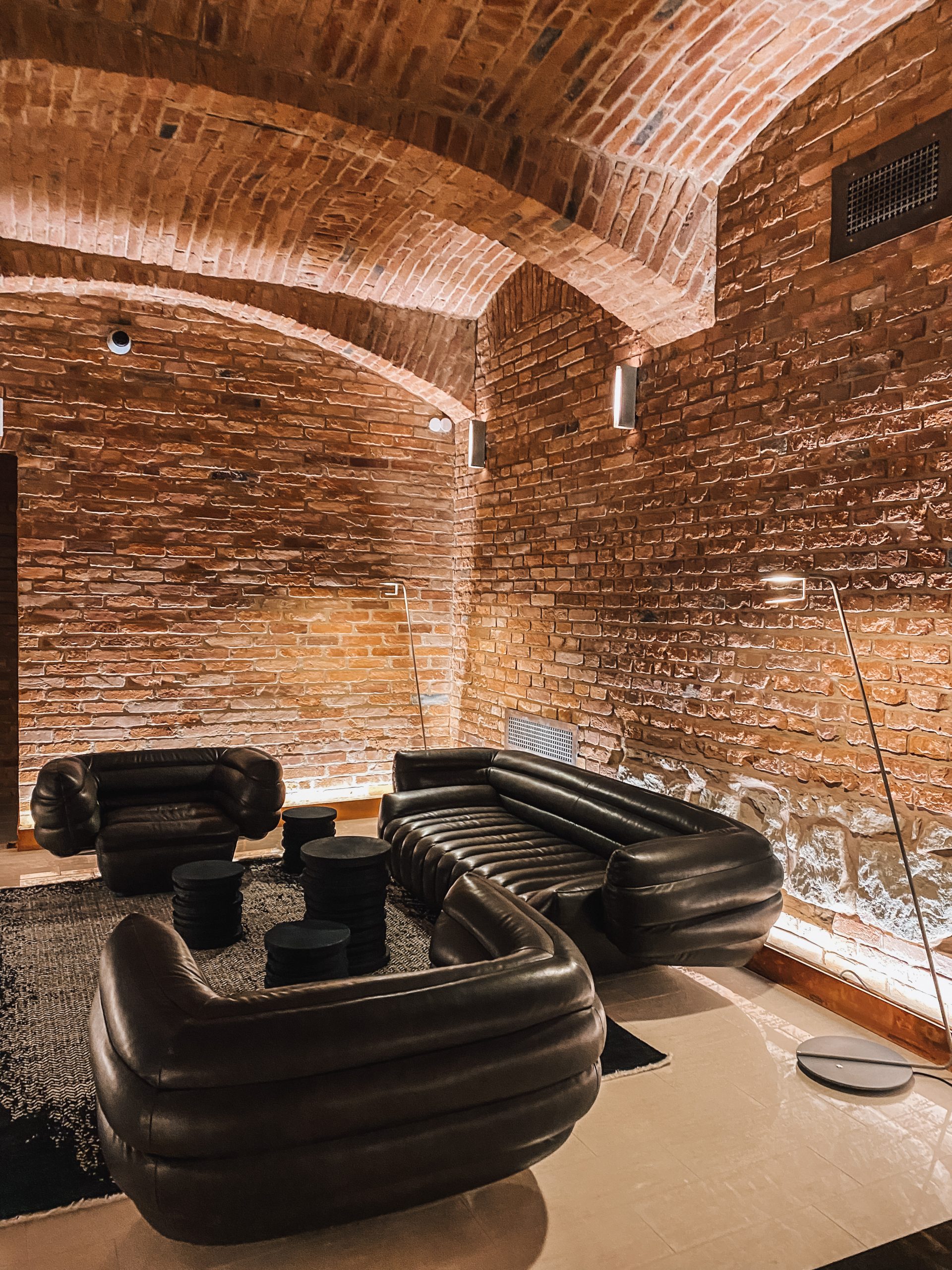 A pyramid stack of empty crystal champagne coupe glasses on a glass table with a dark background and soft lighting.