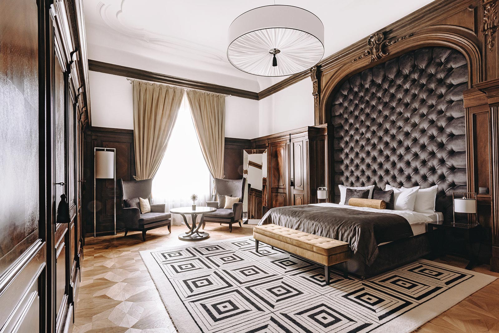 A pyramid stack of empty crystal champagne coupe glasses on a glass table with a dark background and soft lighting.