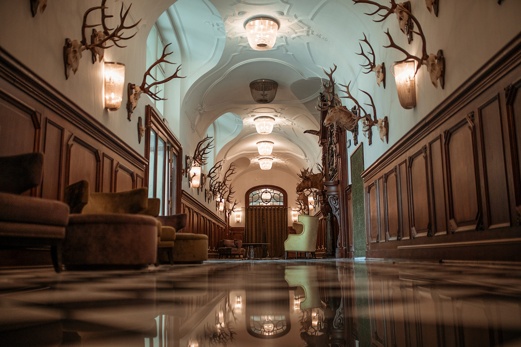 A pyramid stack of empty crystal champagne coupe glasses on a glass table with a dark background and soft lighting.