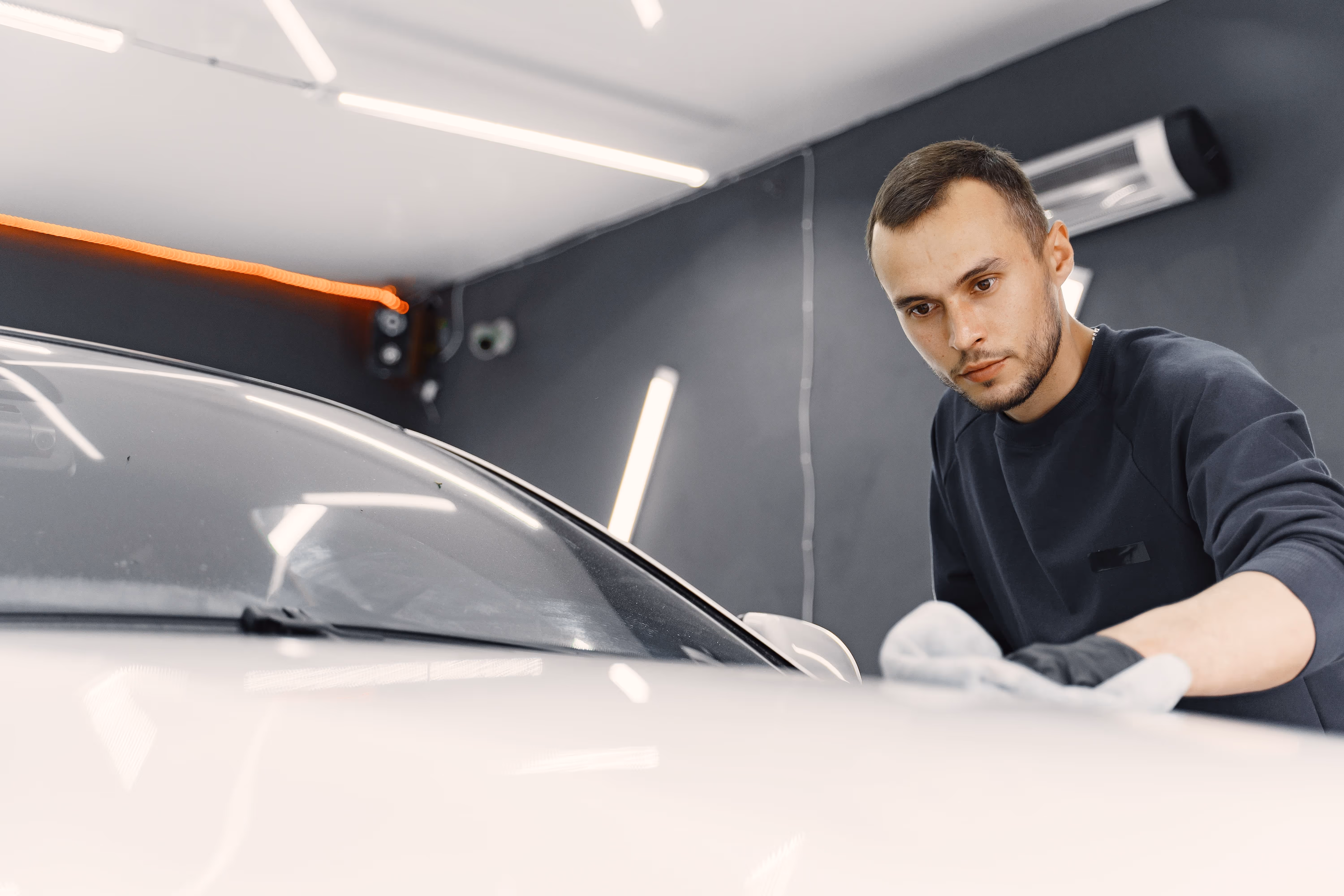 Homem polindo carro em uma estética automotiva