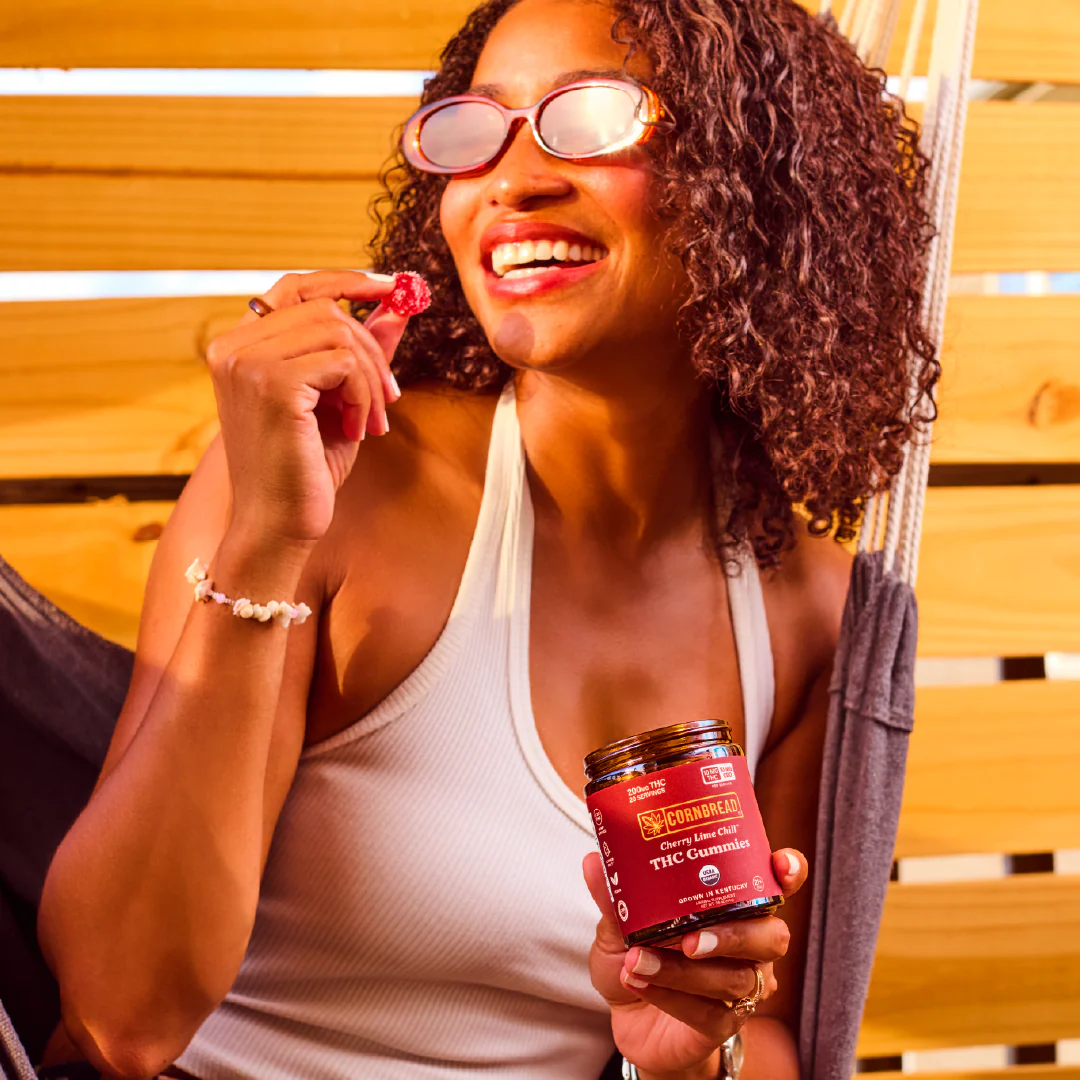 A woman with sunglasses and curly hair holding a gummy