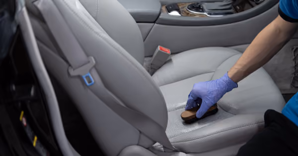 Aplicando hidratante para banco de couro preto em carro de luxo