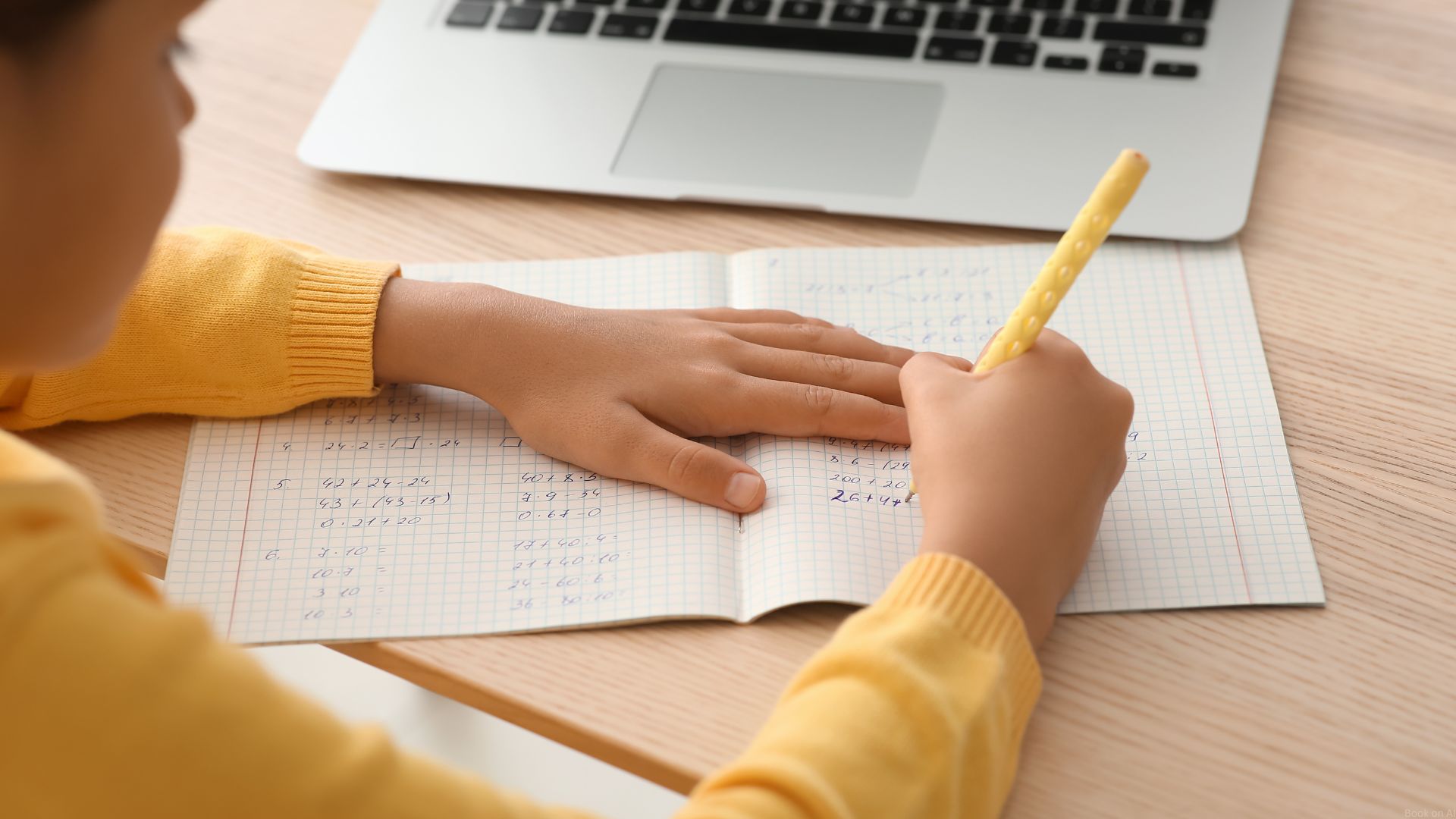 A young student does math tutoring homework in front of his laptop.