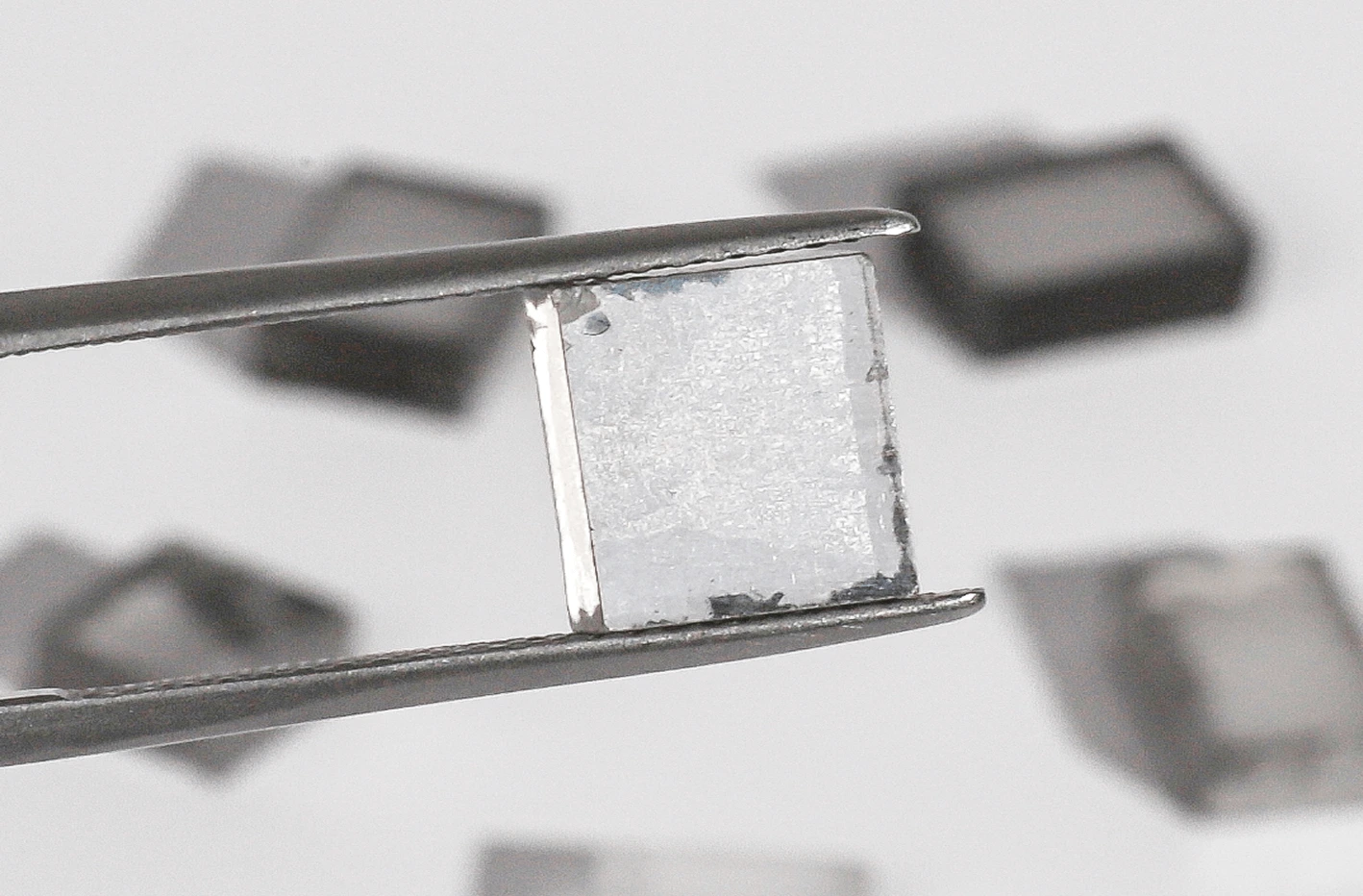 Tweezers holding a rough lab diamond.
