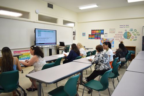 Students inside the classroom, reading and talking to each other.