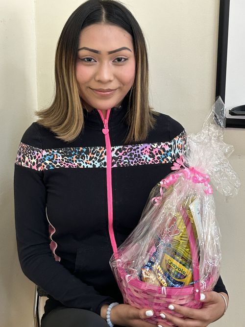 The student is holding the gift basket in her hands.