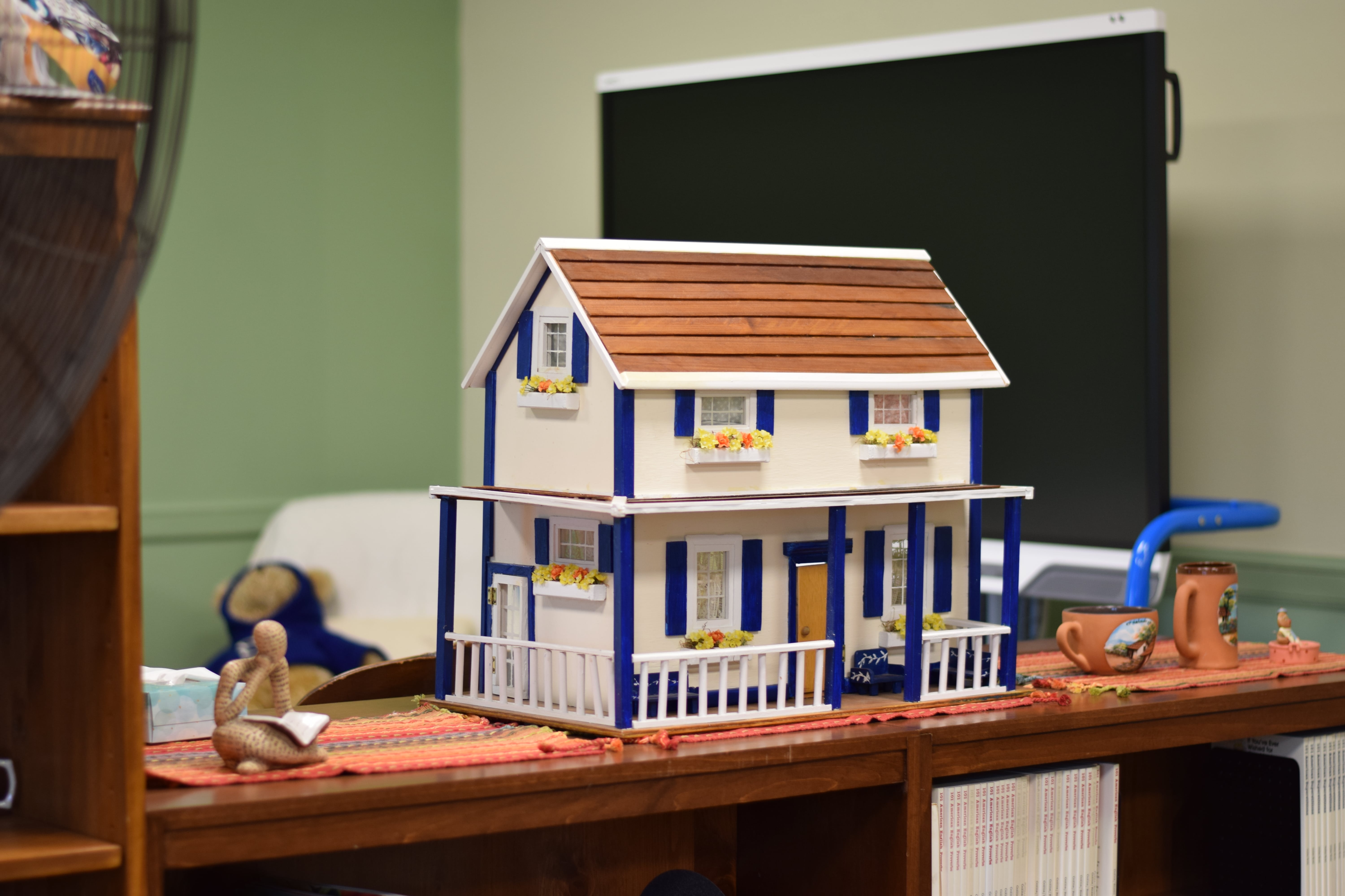 The small hut - a kid's house is standing on the desk, in the library. 