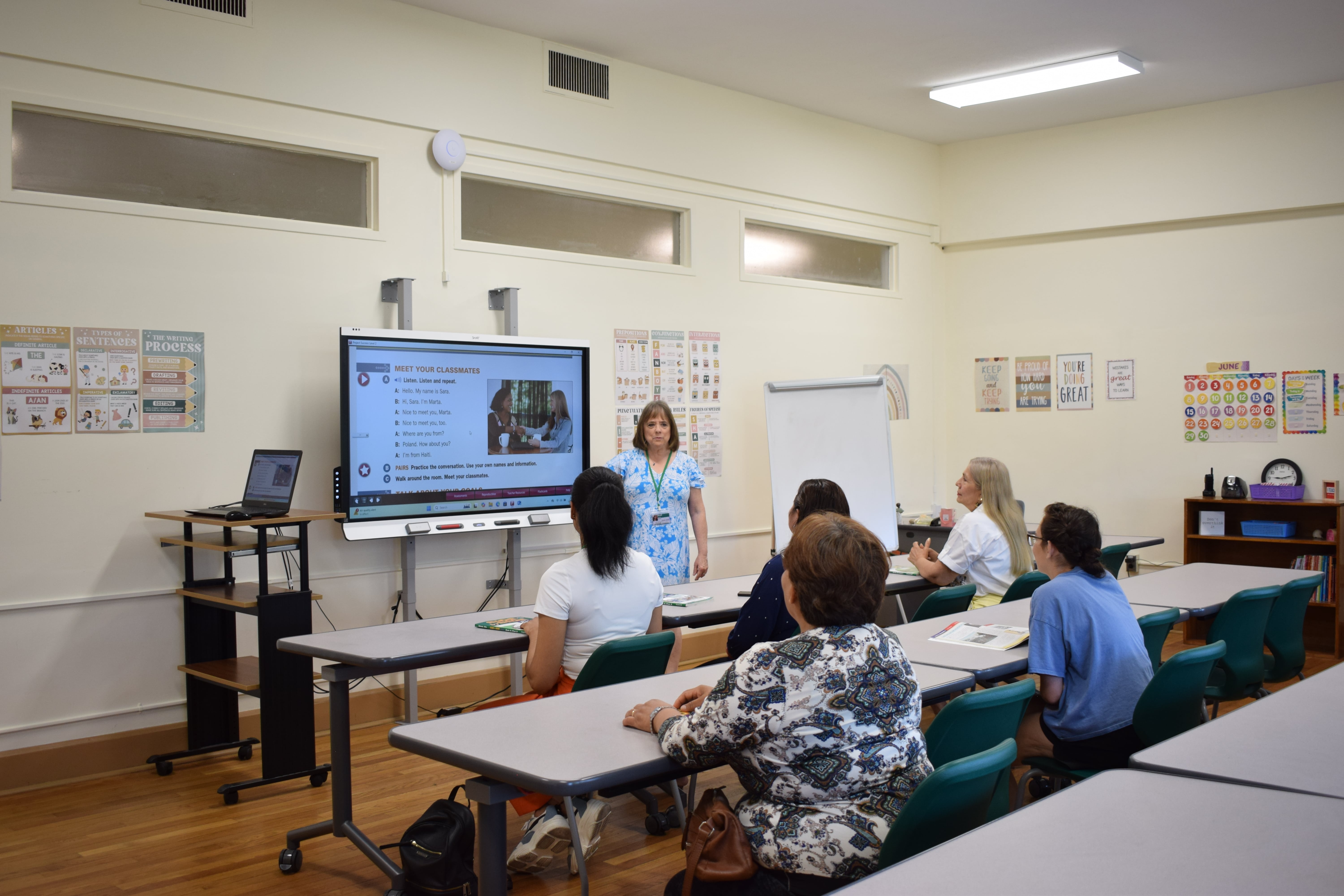 The teacher is talking to a large number of students in the classroom, giving them a take-home assignment. 