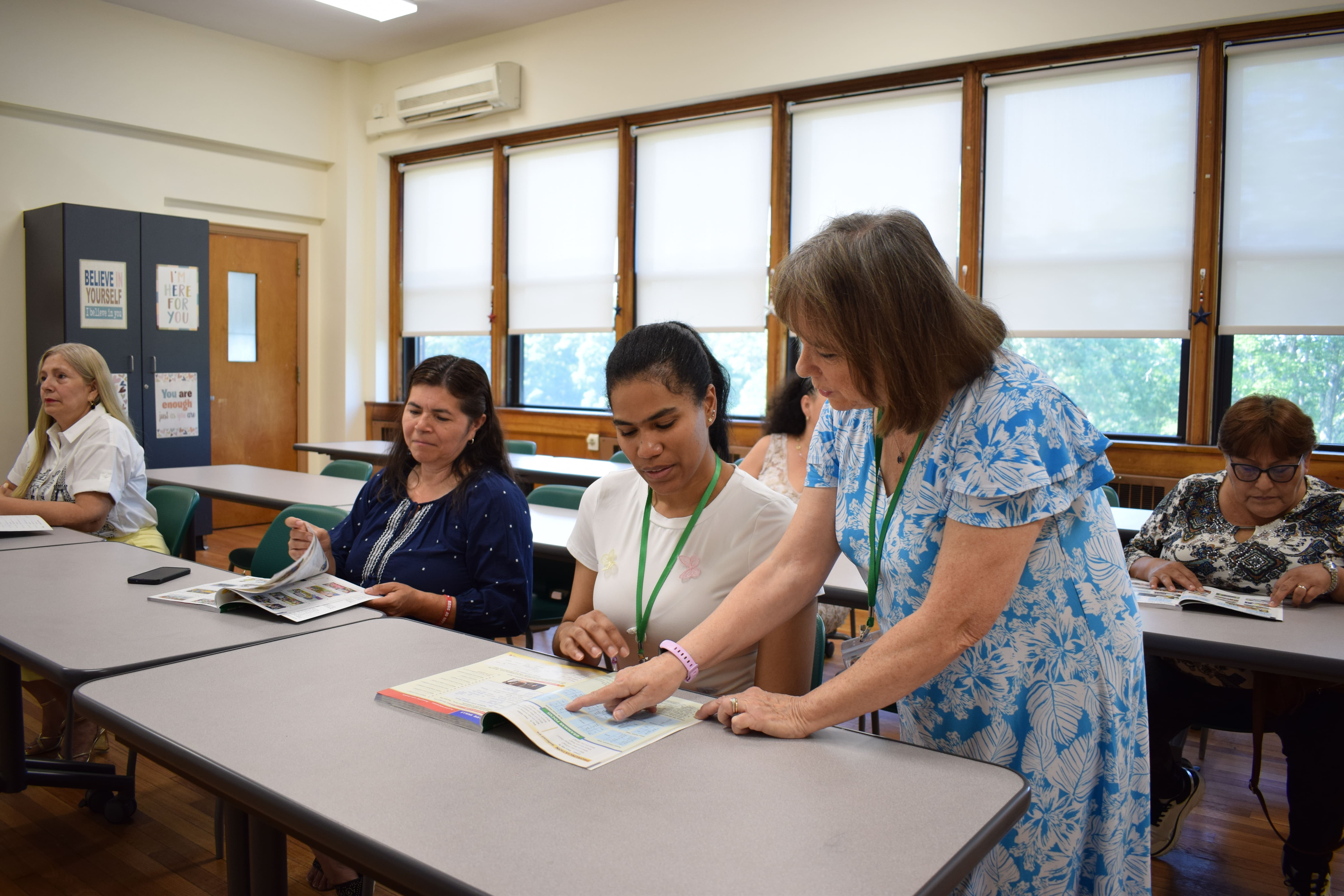The teacher is reading with the student and teaching her correct spelling. 