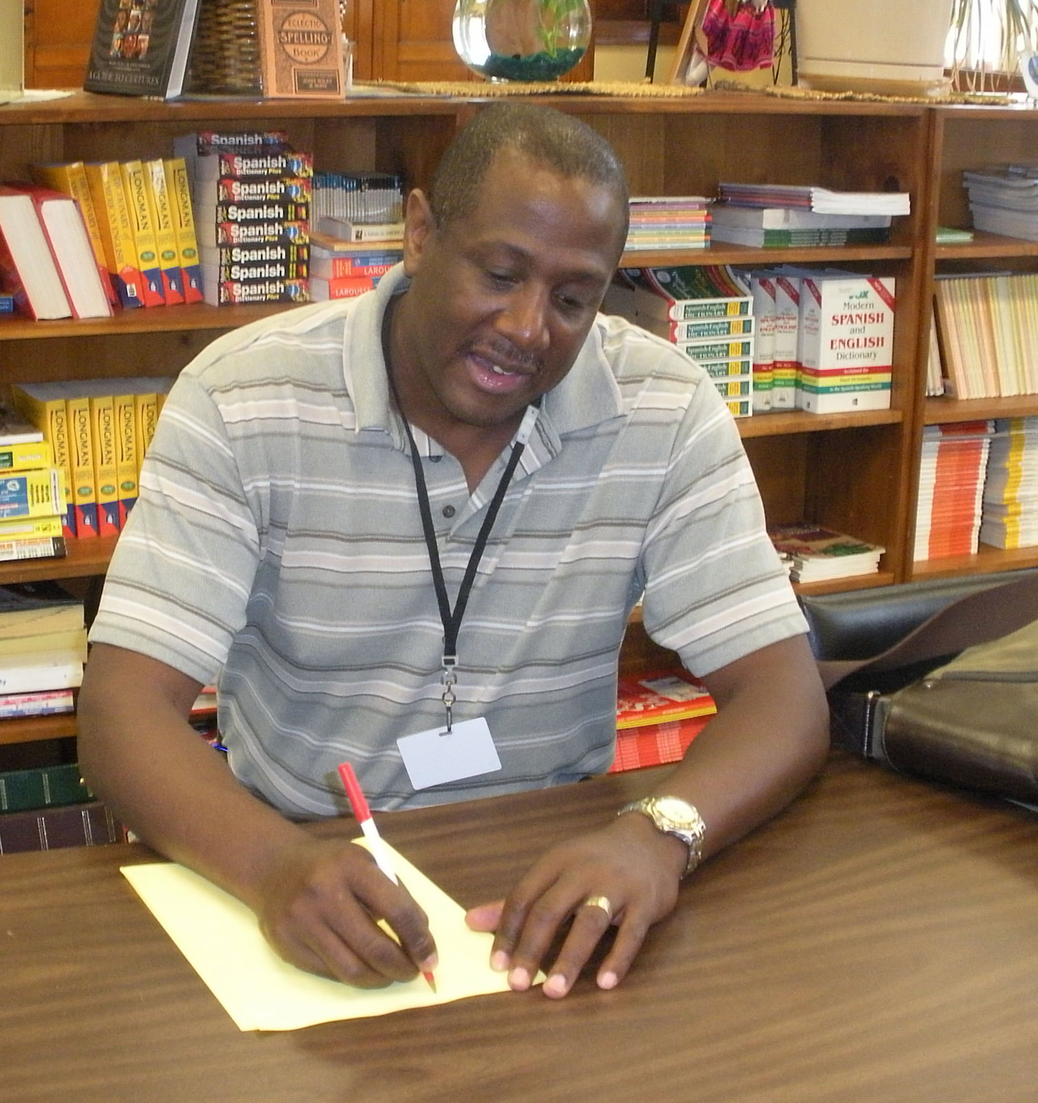 Alex Richardson is sitting at a desk, writing a letter on paper.
