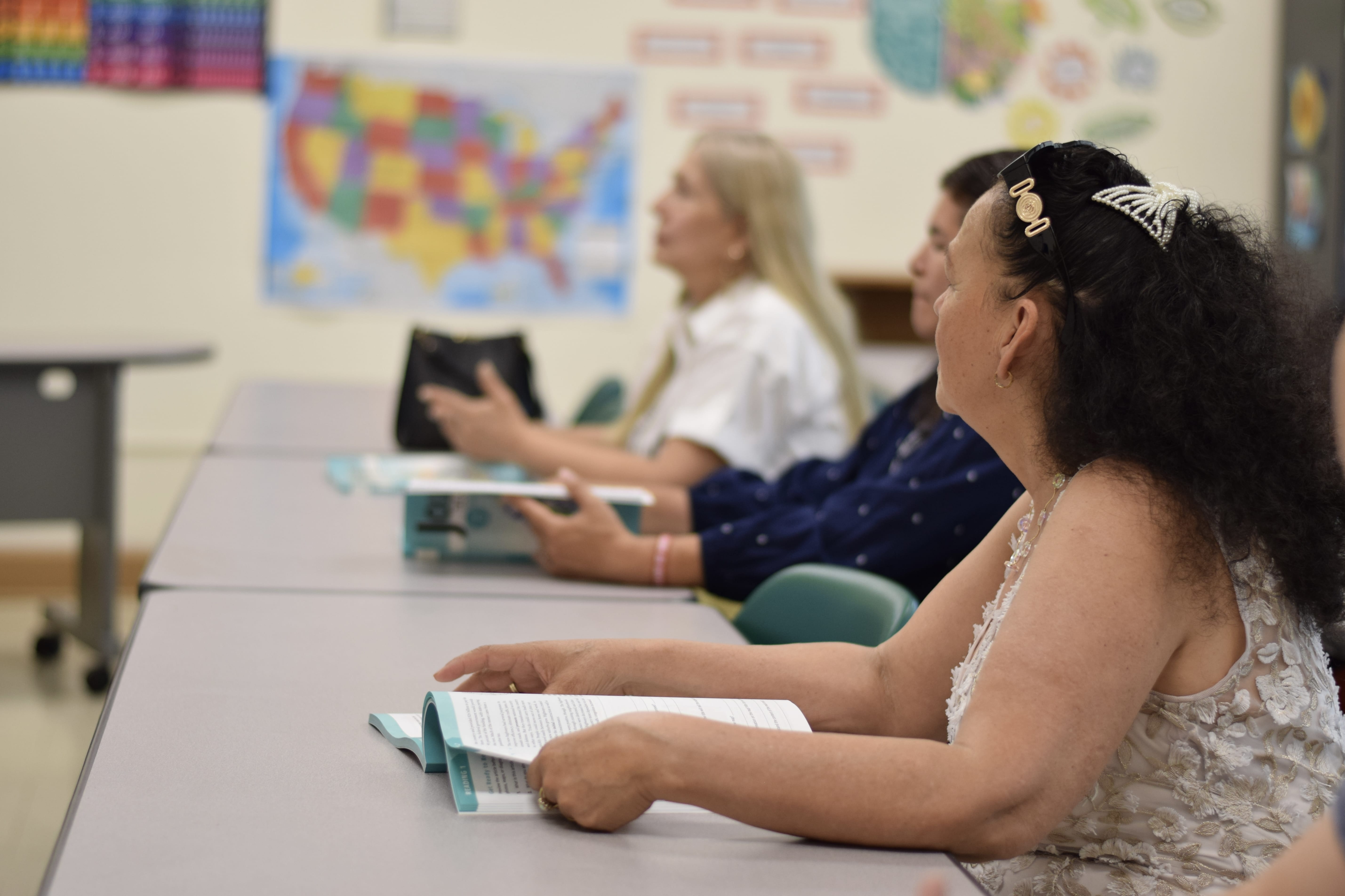 Students sitting at desks holding books in their hands during a classroom lesson.