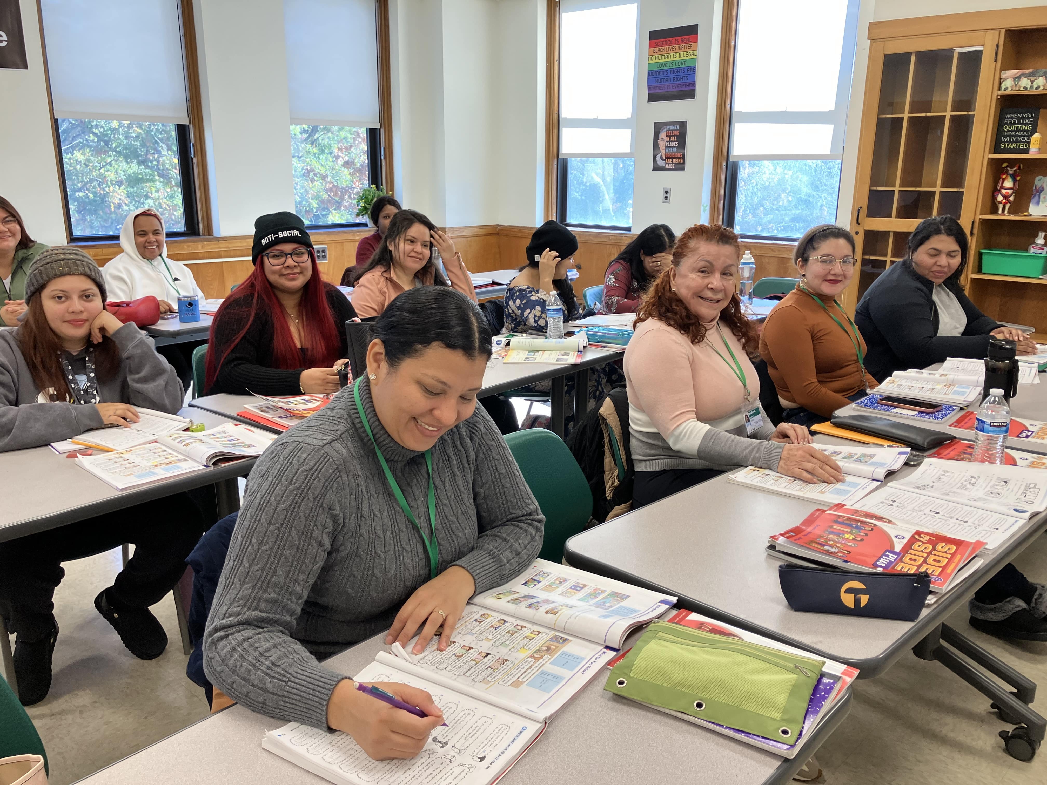 Women studying in a classroom, reading from their books during English as a New Language class. 