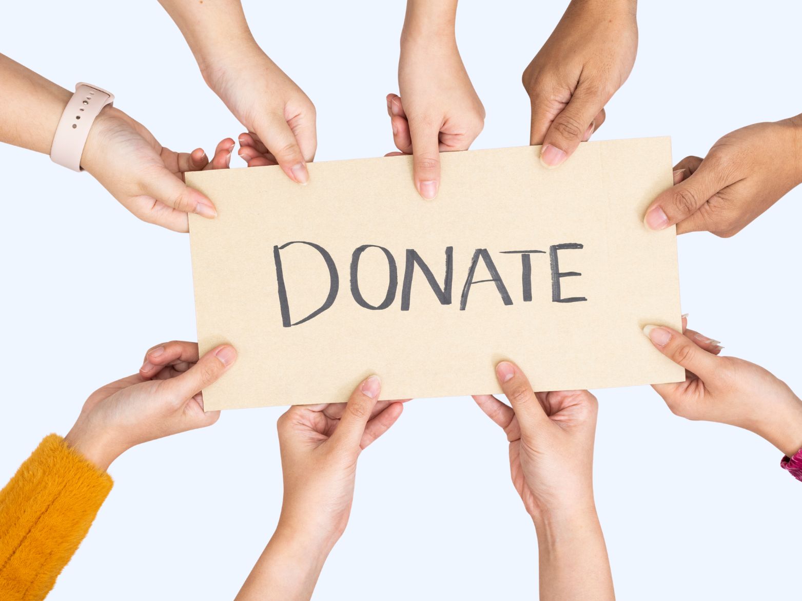 Multiple hands holding a sign that says ‘DONATE,’ close-up with no faces visible.