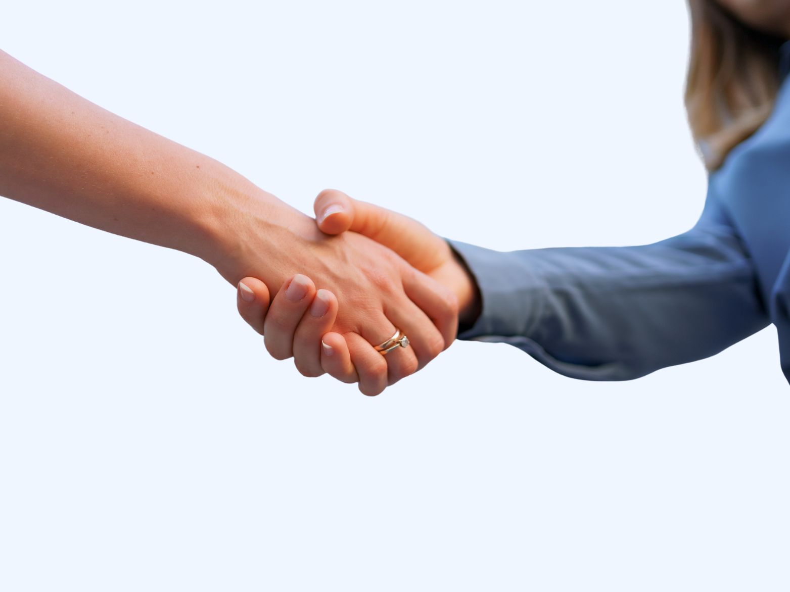 Two women shaking hands, close-up of handshake with no faces visible.