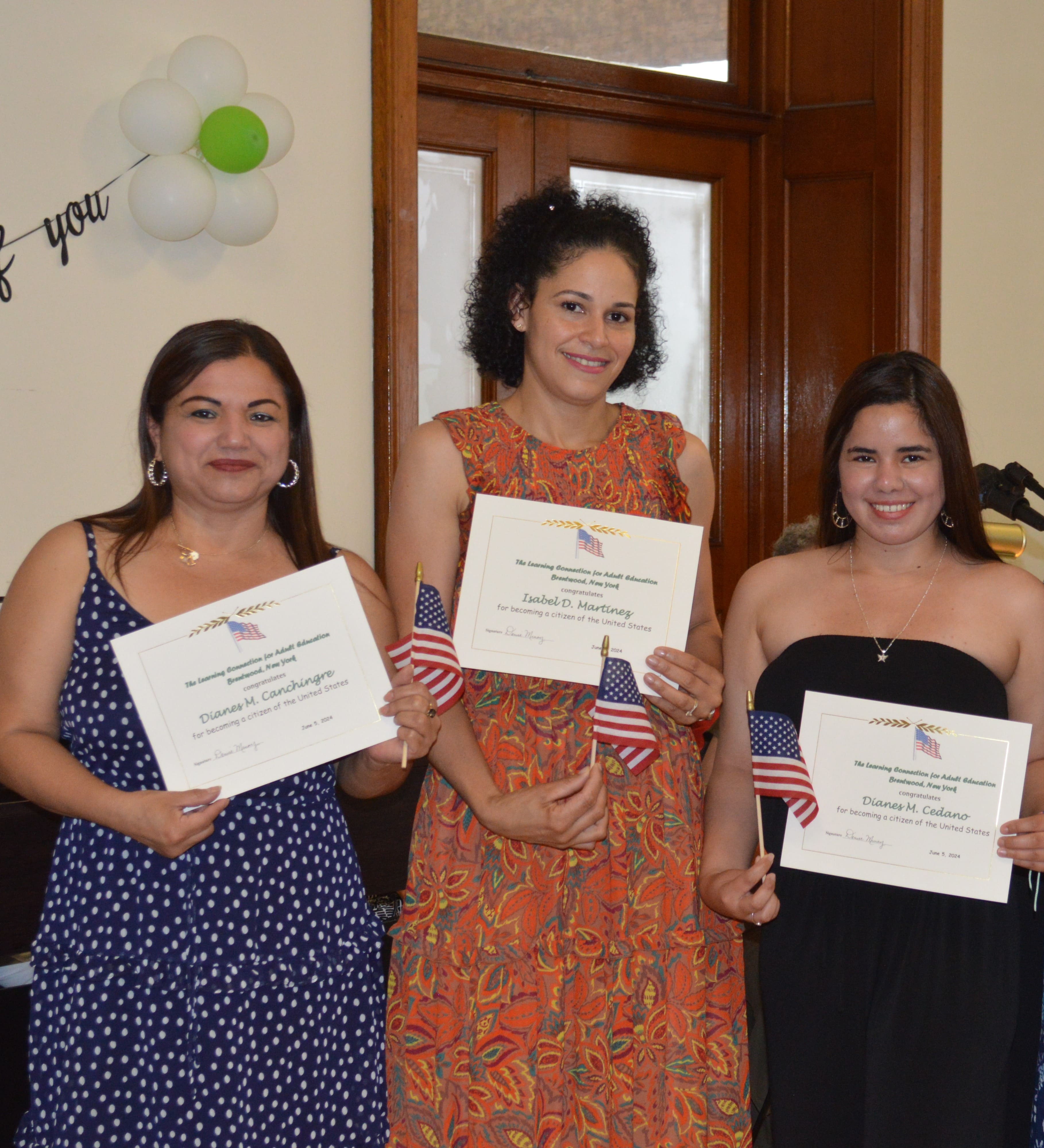Three TLC students holding their citizenship certificates.
