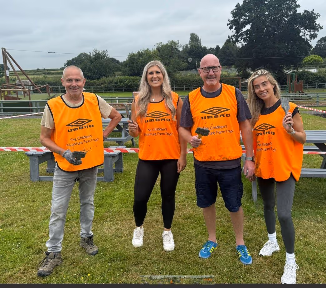 Four volunteers in orange vests at Children's Adventure Farm Trust event
