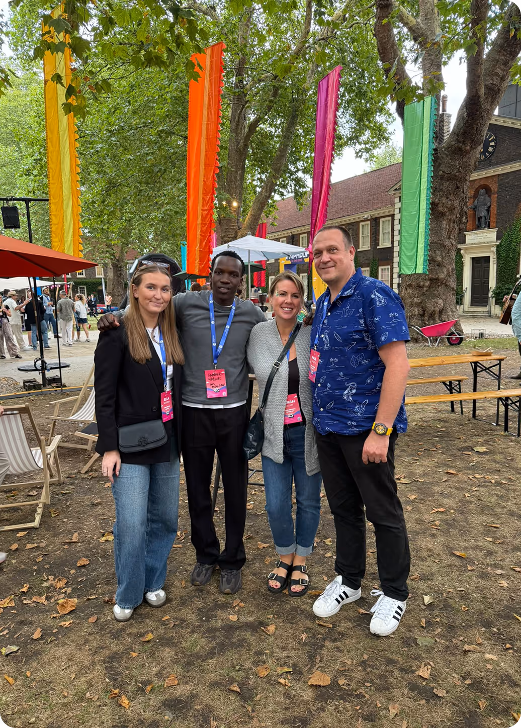 Four colleagues posing together at an outdoor event with colorful flags