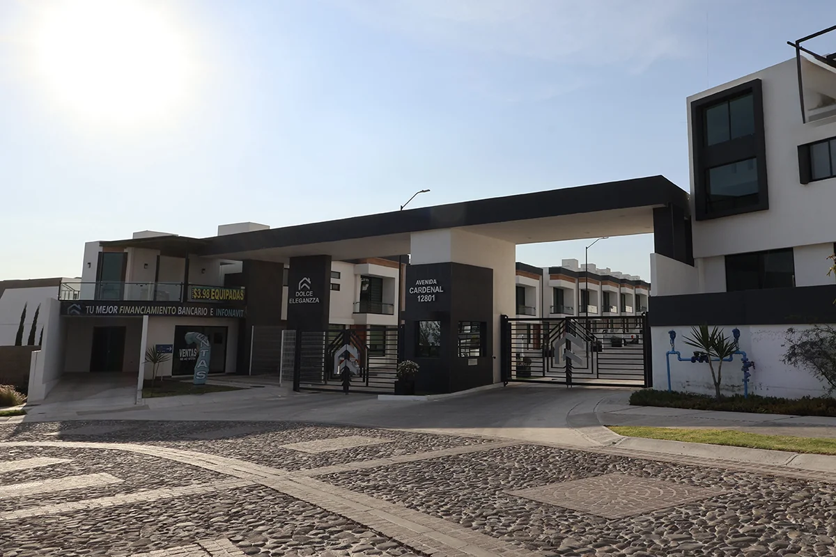 Vista panorámica durante el día y a un costado de un cerro, de fachada de entrada de la privada Dolce Eleganzza en Nuevo Refugio