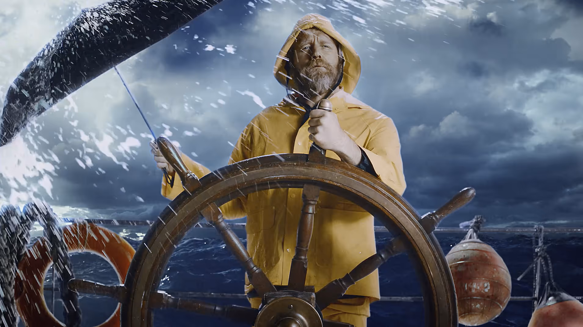 Seasoned sailor in yellow raincoat navigating stormy waters at ship's wheel