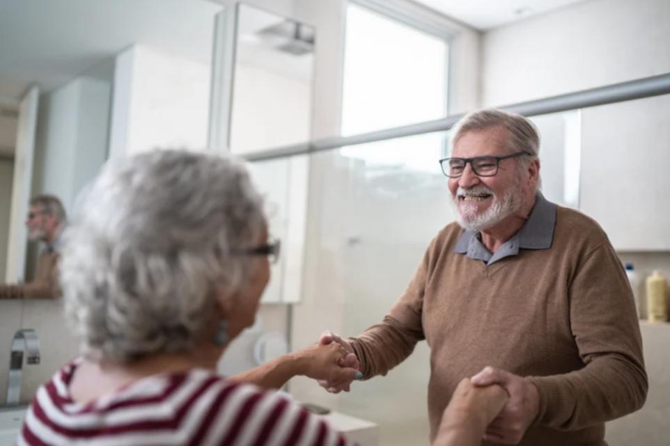 Older man and woman shaking hands and smiling in bright room