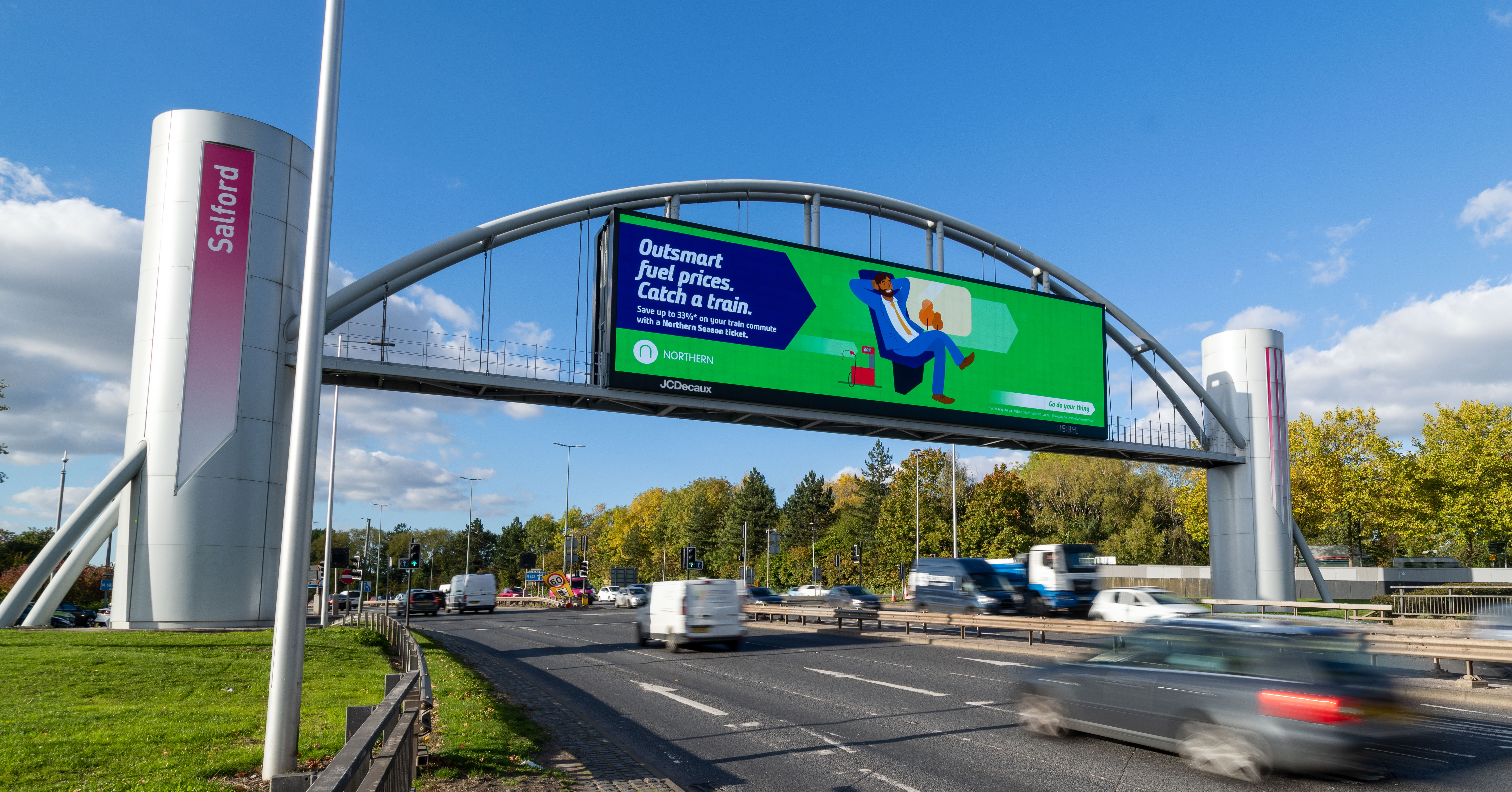 Northern Rail advertisement bridge over busy highway with blurred traffic