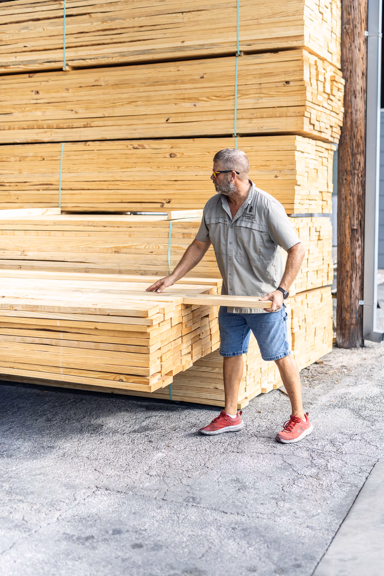 Worker examining stacks of lumber at a lumber supply warehouse