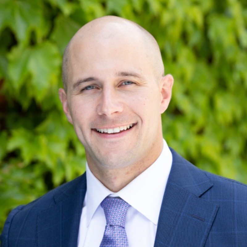 Professional headshot of Nick Wheeler, M7A MBA admissions consulting client, in navy suit