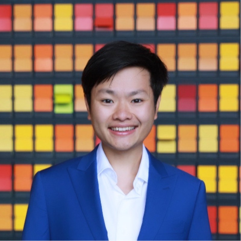 Chase Lin MBA client in blue suit smiling against colorful mosaic background