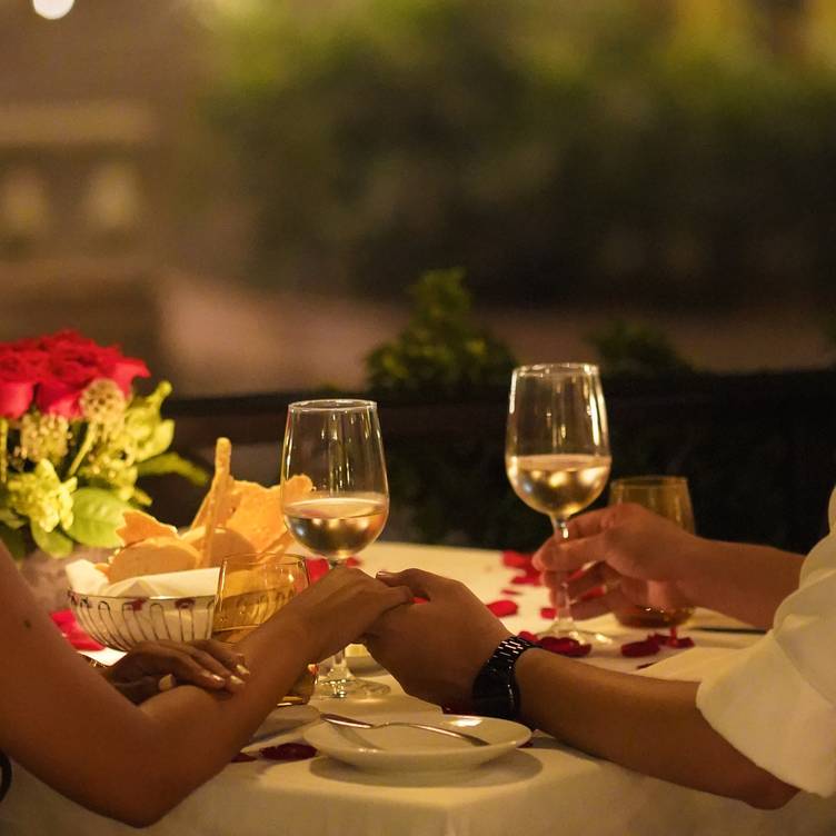 A couple holding hands over a candlelit table at Le Bistro