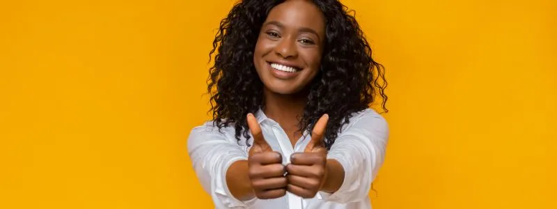 Young professional woman smiling with two thumbs up represting why customers choose to be advocates.