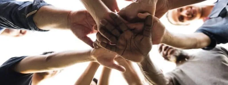 Ground up shot of several people putting their hands together showing that customer reference management is a team sport.