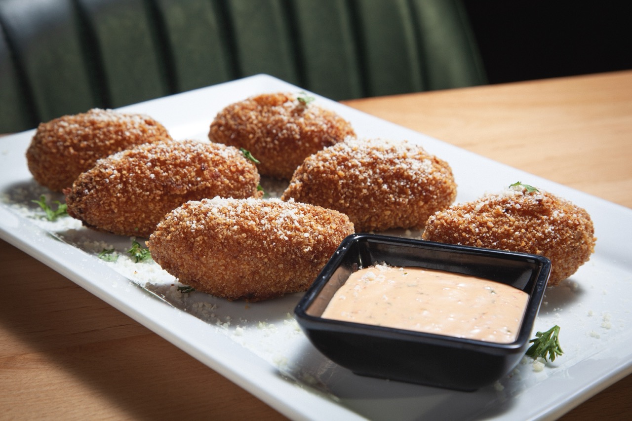 Crispy fried croquettes served on a white plate with roasted garlic aioli dipping sauce at DeWolf Brewing, Victor NY
