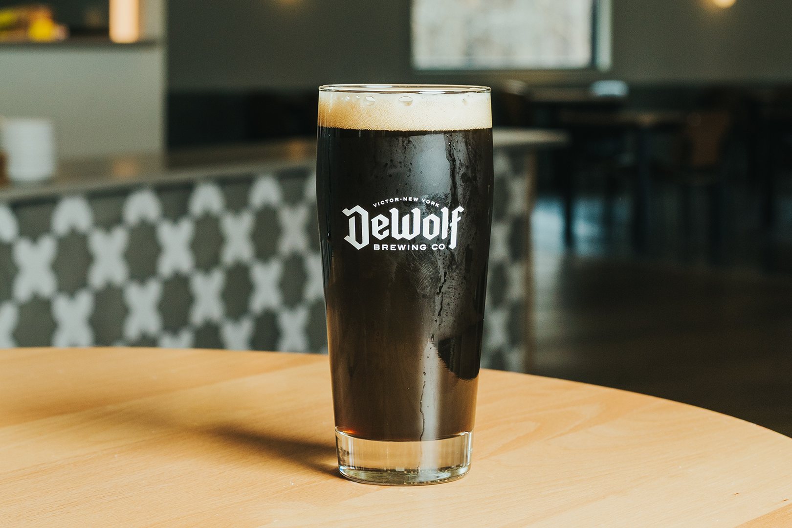 A jet black pour of The Traveller Irish Stout with a thin creamy head in a DeWolf Brewing Co. glass, Victor New York