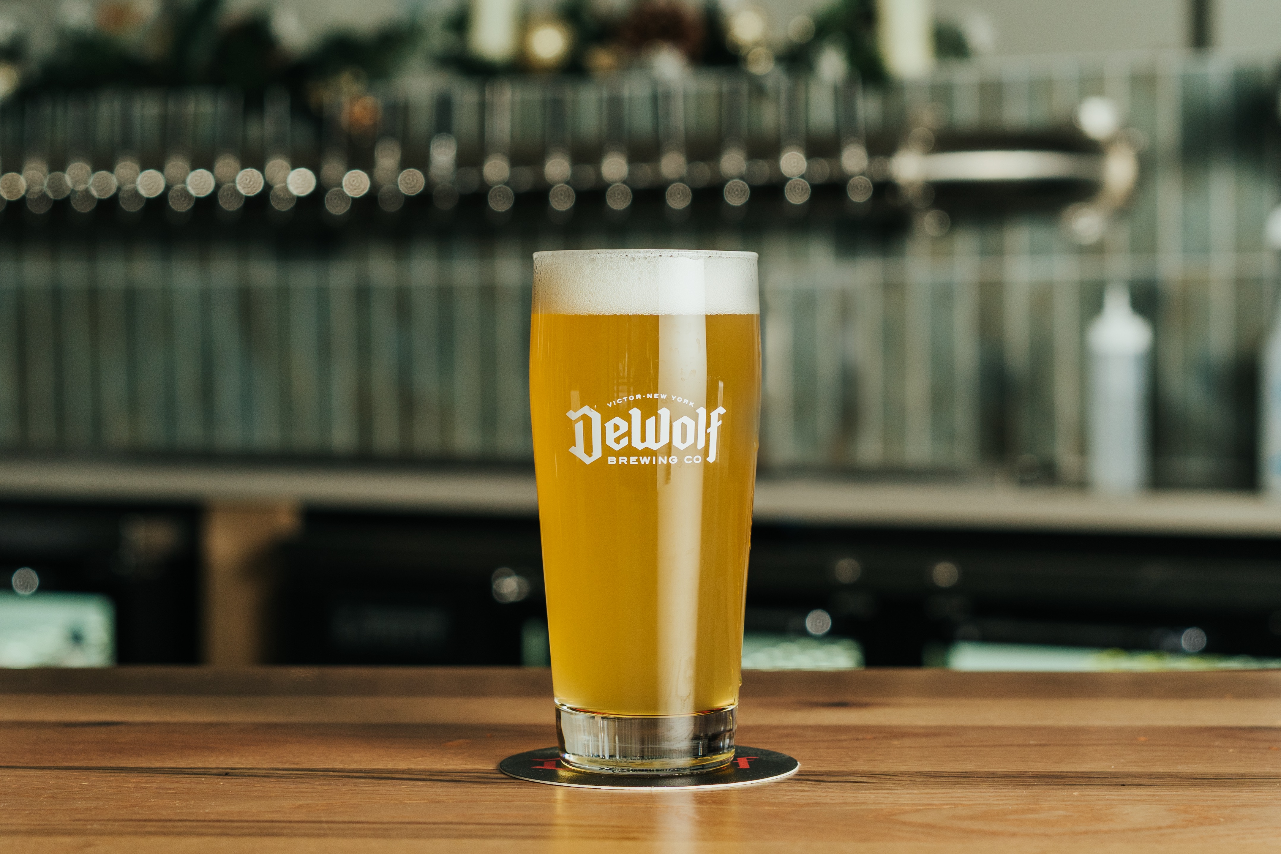 A hazy golden pour of Tart and Sweet Mango light fruited sour ale in a DeWolf Brewing Co. glass, Victor New York