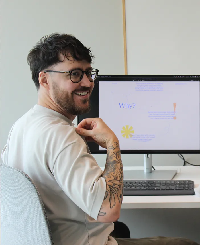 Félix at his desk, looking back at a colleague and smiling