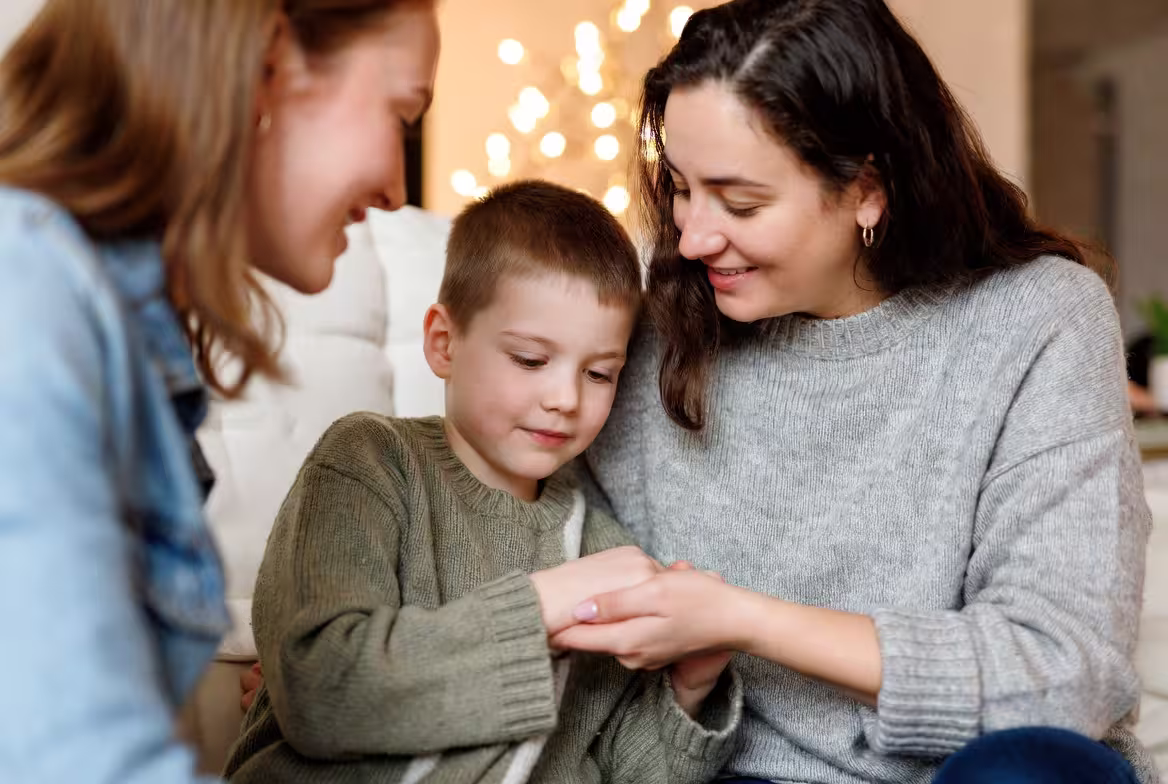 Caregiver smiling with compasion while holding hands with a child