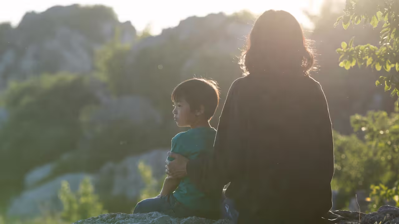 Parent and child sitting outdoors during a peaceful family moment.