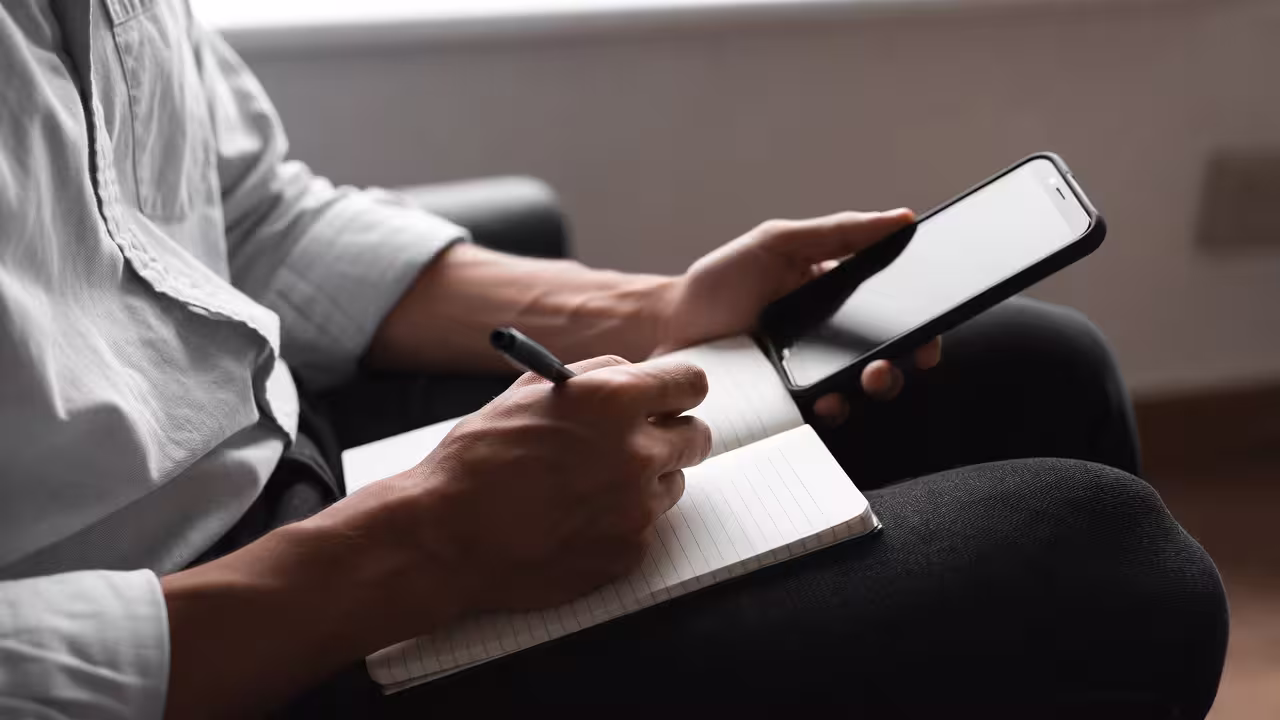 Hands writing notes in a notebook during a calm planning moment.