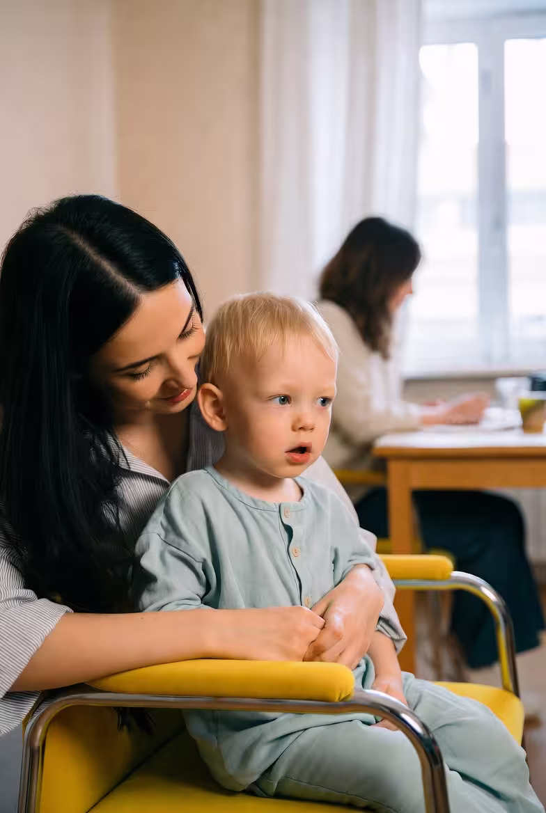 Mother helping a young child with a learning or support activity at home.