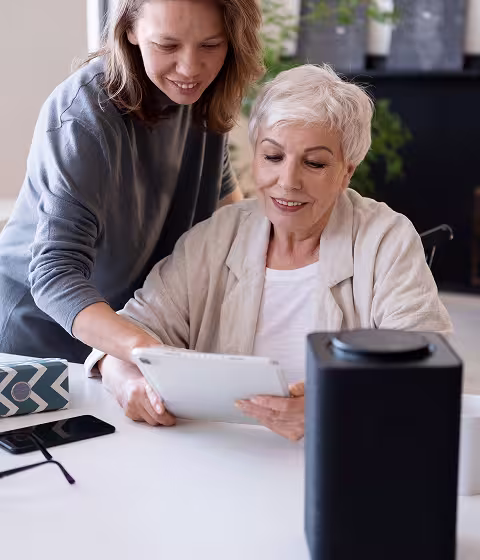 Caregiver helping an older adult review important documents at a table.