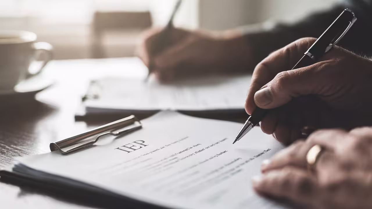 Close-up of a person completing IEP paperwork and special education documents.