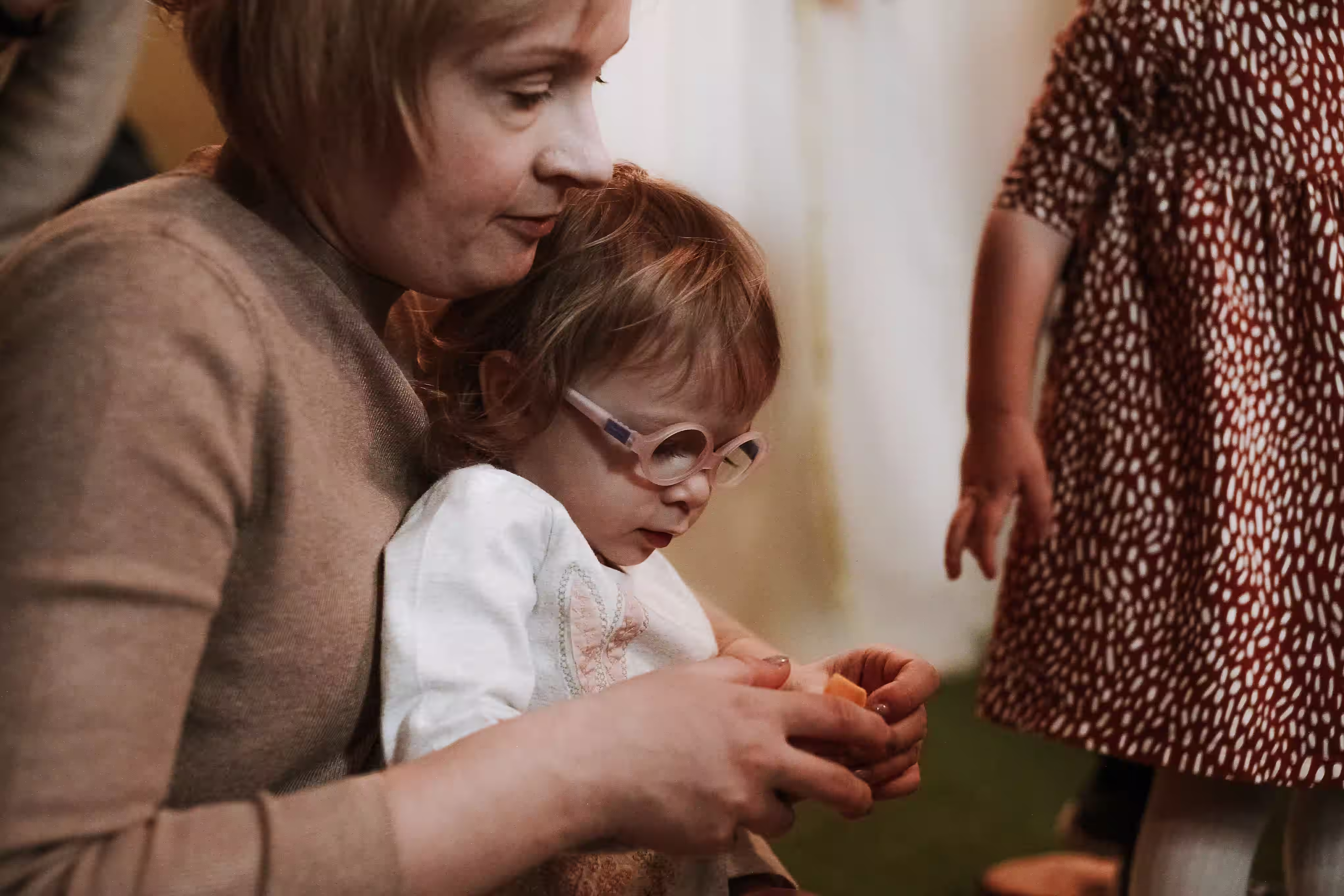 Adult sitting close to a young child with glasses during a quiet support moment.