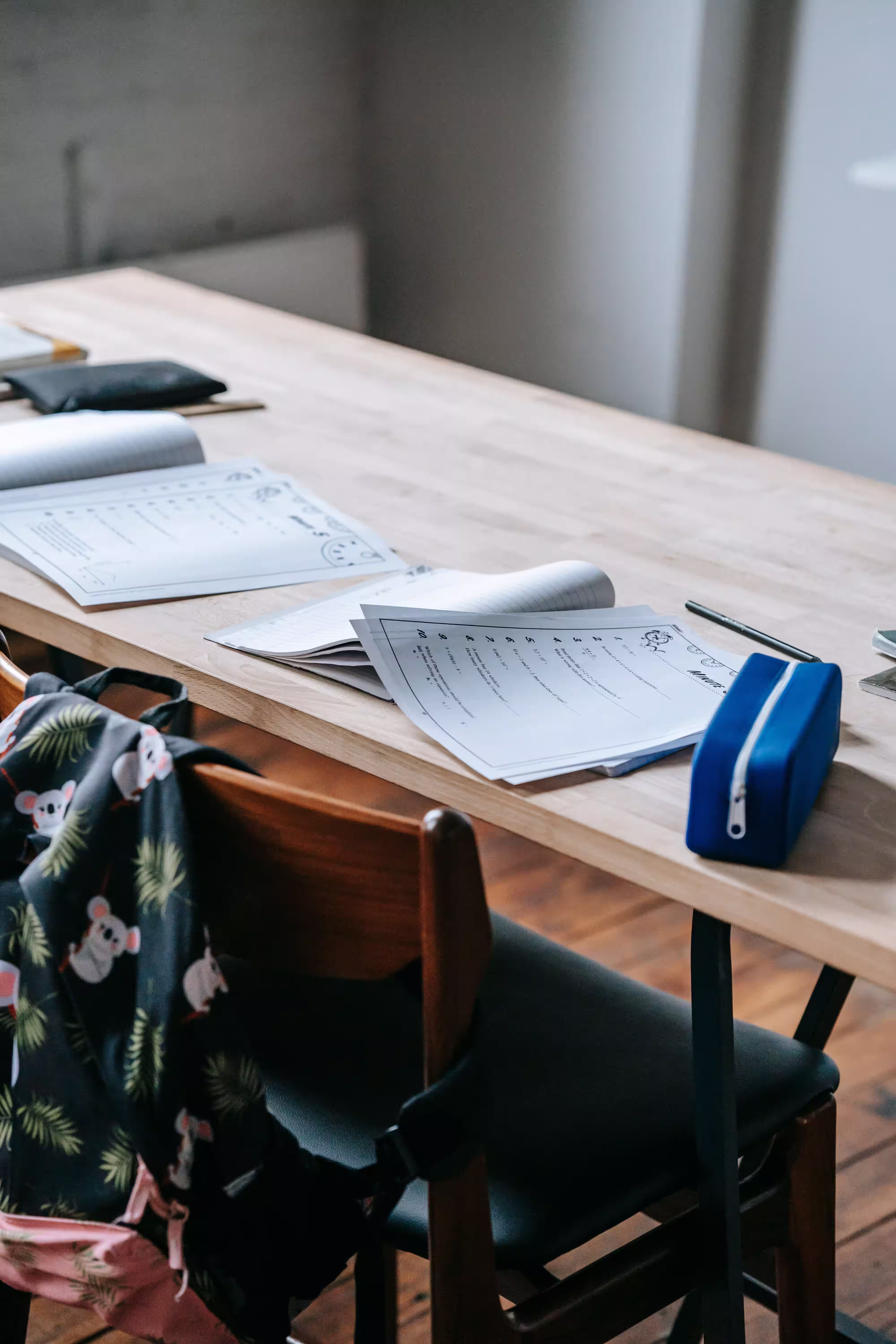 School paperwork, forms, and a child’s backpack on a table before a school support meeting.